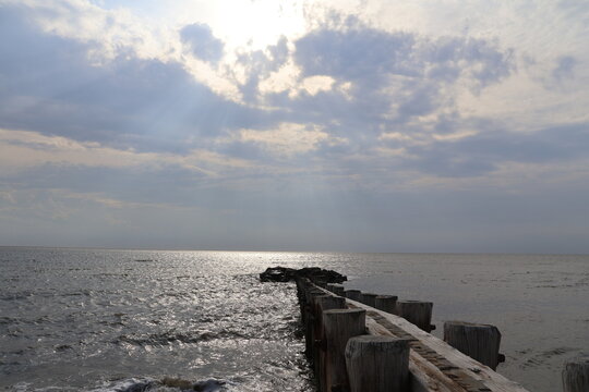 A old nautical looking jetty sitting out on a placid bay during a peaceful summer evening.