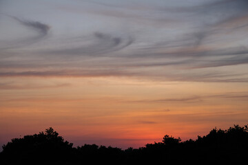 Fototapeta premium Vibrant orange sunset with three silhouettes