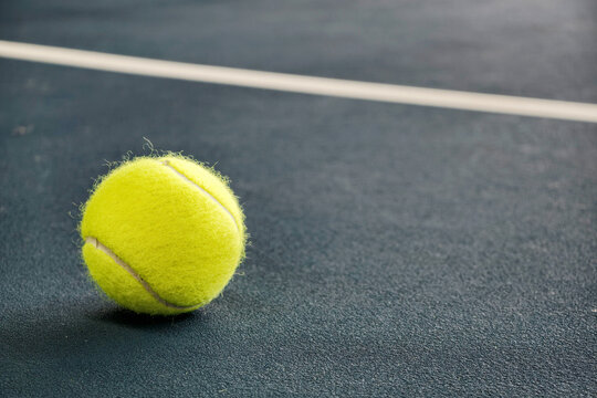 Tennis ball on a blue court surface