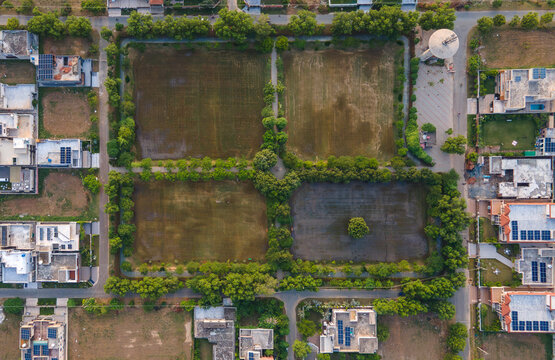 Aerial view of a residential neighborhood with a central park divided into four sections by tree-lined paths, houses with solar panels and a water tower in Lahore, Punjab, Pakistan.