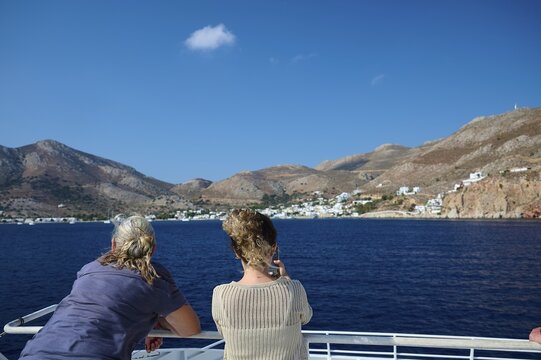 Two people on a boat enjoying the view of a coast, Zero Waste Island, Tilos, Dodecanese, Greek Islands, Greece