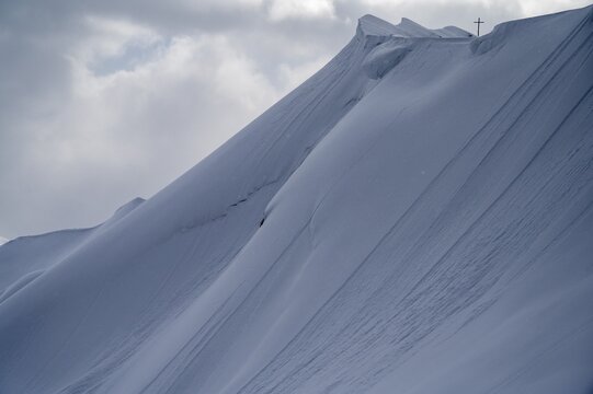 Summit cross of the H&ouml;ferspitze with covered summit ridge and mountaineers, Baad, Kleinwalsertal, Vorarlberg, Austria