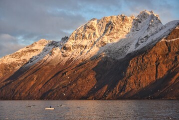 Whale watching boats in a fjord with majestic snow covered mountains during sunset  © youness
