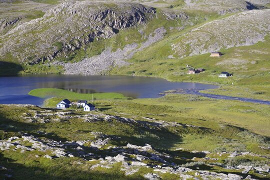 Green land with barren, stony mountains and a lake, single cabins, Gamvik, Arctic, Finnmark, Norway