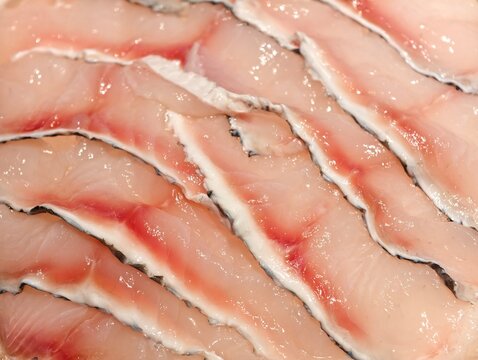 High-angle close-up shot of fresh raw snakehead fish fillets with skin neatly stacked