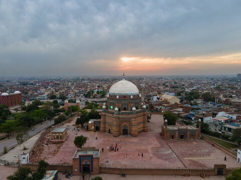 Aerial view of the historic Tomb of Shah Rukn-e-Alam with its iconic dome and intricate brickwork, surrounded by the urban landscape of Multan at sunset, Multan, Punjab, Pakistan.