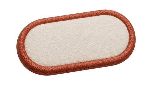 Close up of a blank oval fabric patch with a cream woven center and rust colored embroidered border, isolated on a transparent background for custom label design.