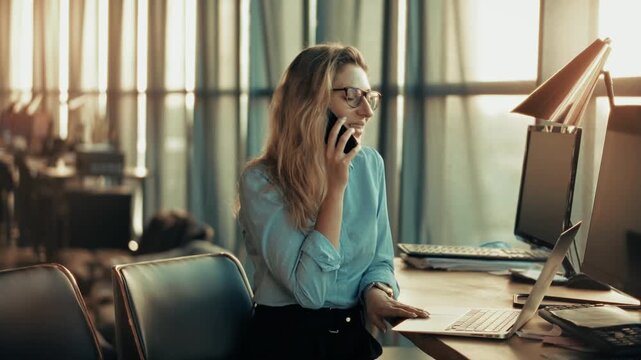 Businesswoman Talking On Smartphone And Working On Laptop At Office. Business Communication 