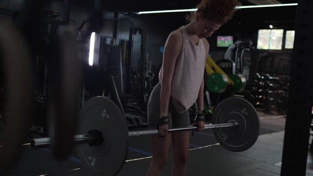 Strong fitness woman performing barbell bent-over row exercise