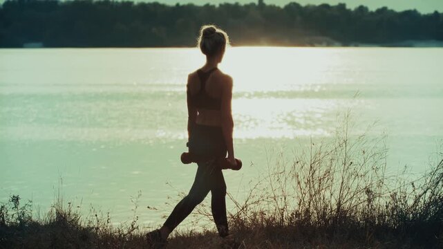 Athlete Doing Lunges Holding Dumbbells Near River At Sunset. Workout Outdoor Training. Strength Training 