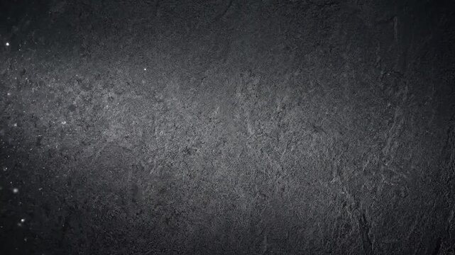 Dark textured concrete wall with moving light beam and floating dust