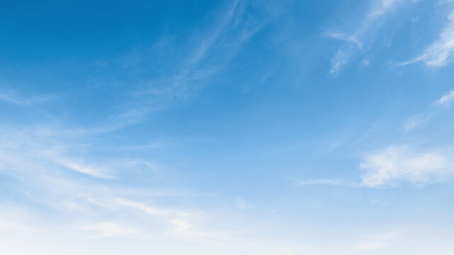 Clear blue sky with soft, wispy clouds drifting gently