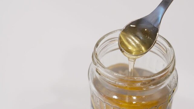 Slow motion of a spoon stirring honey in a jar