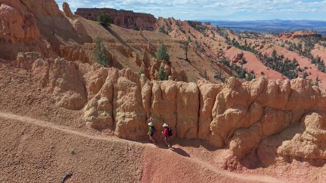 Aerial scene of man and woman hiking on the Buckhorn trail surrounded by hoodoos near Bryce Canyon in Utah on a clear day.