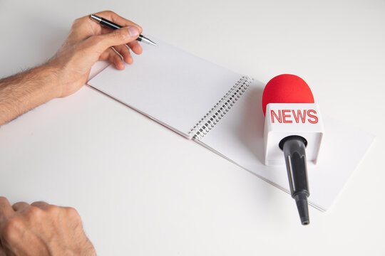 Journalist writes on notepad with a microphone on a white background.