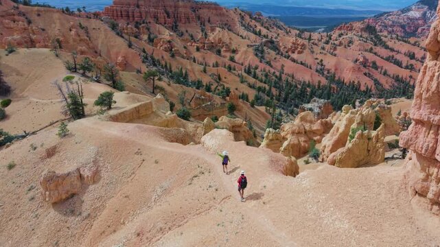 Aerial view of man and woman hiking on Buckhorn trail in Bryce Canyon, surrounded by hoodoos and stunning landscapes