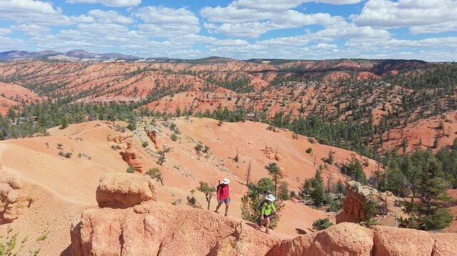 Aerial view of man and woman hiking along the Buckhorn trail surrounded by hoodoo rock formations in Bryce Canyon, Utah under a clear sky