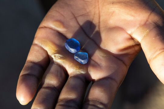 Hand holding two rough blue sapphires, Isalo, Madagascar