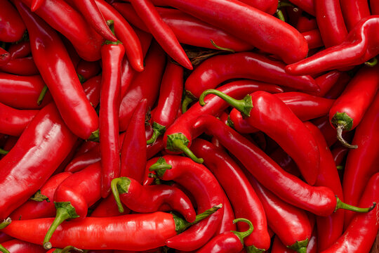A top view macro texture of red chili peppers at an autumn agricultural market. Seasonal vegetable retail, and spice reserves