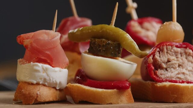 Tapas Spanish pinchos assortment, Basque pintxos with jamon iberico, tortilla, shrimp, stuffed piquillo pepper and egg on bread, traditional bar food close up