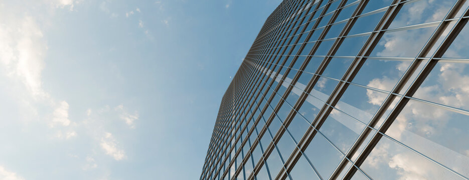 Low angle view of a modern glass skyscraper reflecting a bright blue sky with soft white clouds