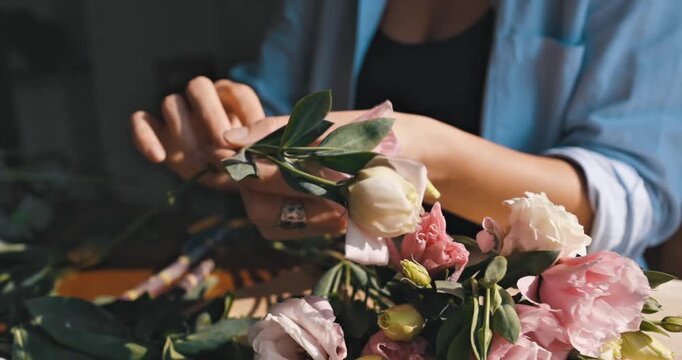 Close Up View of Florist Hands Arranging Delicate Pink and White Lisianthus Flowers in a Bright Floral Studio Workshop
