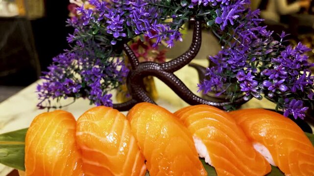 Fresh salmon sushi pieces arranged tightly on round serving plate with bamboo mat liner, glossy orange fish, leaf garnish, soft marble table backdrop, premium dining presentation
