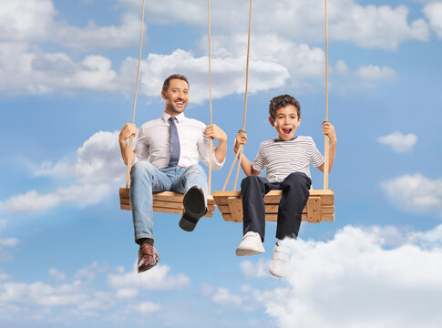Father and son having fun on wooden swings