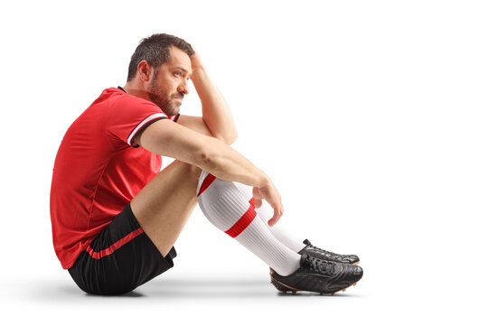 Sad football player sitting on the ground after losing a match