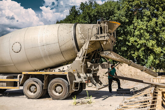 A mixer truck discharges concrete for a landscaping task at a construction site. The equipment enables the efficient delivery of materials