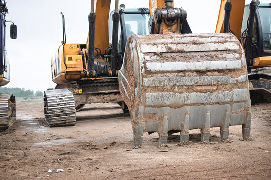 Excavators lined up at a construction site preparing for earthmoving operations on a cloudy day