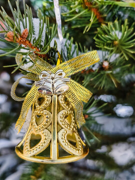 A golden bell ornament hangs from a decorated natural Christmas tree. The scene captures the spirit of the New Year and Christmas festivities