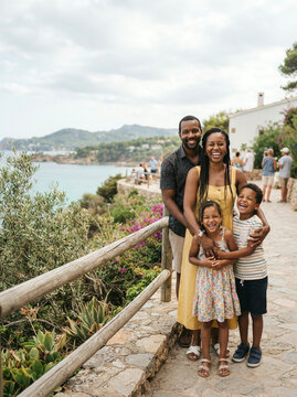 Family of four smiling at a stone railing in yellow and striped clothes