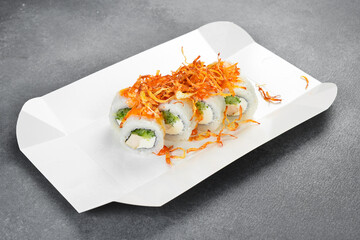 Japanese sushi rolls topped with crunchy fried onion and spicy sauce served in white takeaway paper box. Fresh rolls filled with cream cheese. Tasty food. © Yaruniv-Studio