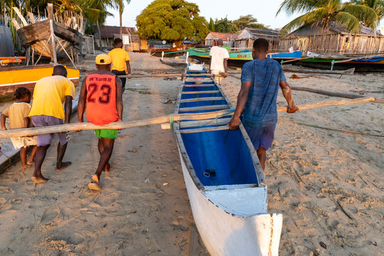 Men carrying a wooden canoe along the beach, Belo sur Mer, Madagascar
