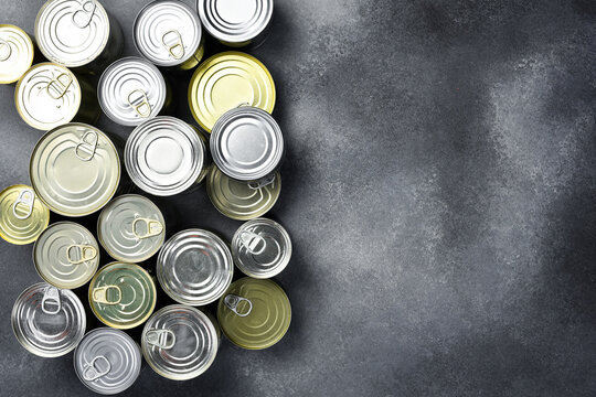 A set of metal cans with food supplies. Canned food. On a gray stone background.
