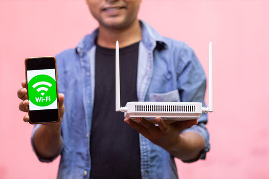 Person Holding Smartphone Displaying Wi-Fi Symbol with Wireless Router
