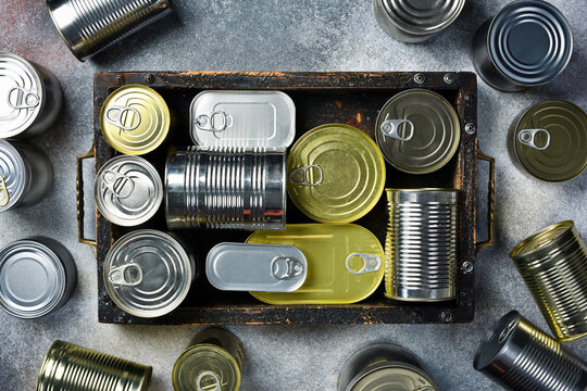 Metal cans with canned goods. A wooden box with food supplies. Close up.