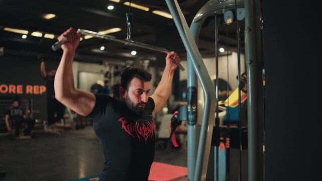 Muscular male athlete pulling lat pulldown bar towards upper chest on selectorized gym equipment focusing on latissimus dorsi activation and strength training.