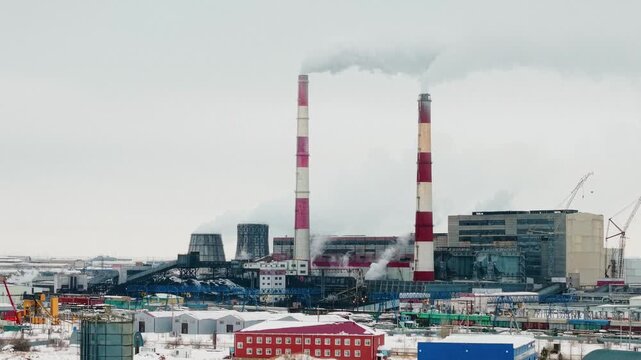 Aerial view of a coal power plant with smoking chimneys and cooling towers in winter