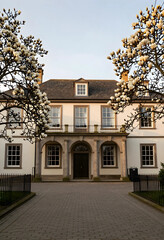 Obraz premium Luxury real estate and spring season, historic manor house with blooming magnolia trees and stone architecture in a peaceful garden setting at sunset