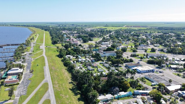 Aerial view of the town of Pahokee situated along the shores of Lake Okeechobee with a marina, residential areas, and lush greenery in Pahokee, Florida, United States.