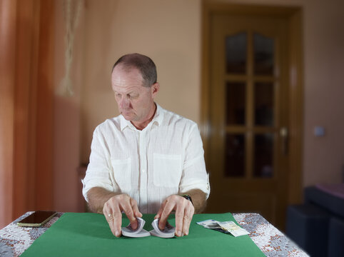 Man handling playing cards on a table in a room during daytime