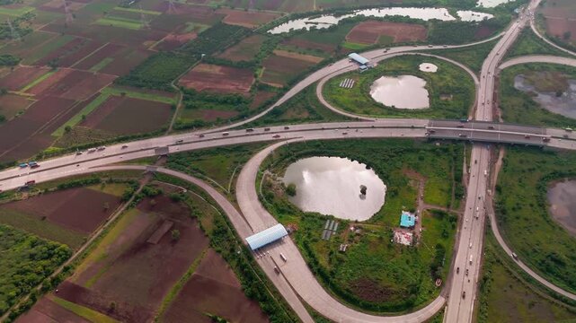 Aerial view of a highway interchange with a toll plaza surrounded by agricultural fields and ponds in Bharuch, Gujarat, India.