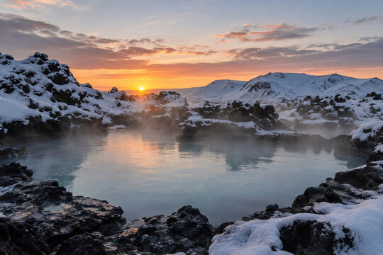 A quiet volcanic hot spring surrounded by snow and dark rocks at dawn