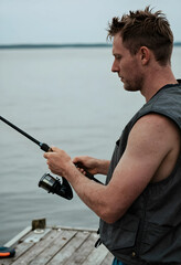 Fototapeta premium Leisure and relaxation, man fishing on a wooden pier at the lake for outdoor recreation and hobby lifestyle with focus on patience and mindfulness