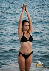 Fototapeta premium Mindfulness and wellness, woman practicing yoga on a wooden pier by the sea for stress relief and healthy lifestyle balance during summer vacation