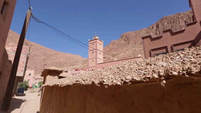 Traditional berber mudbrick architecture with a mosque minaret in the stunning todra gorge, morocco, showcasing the unique reddish color of the atlas mountains landscape