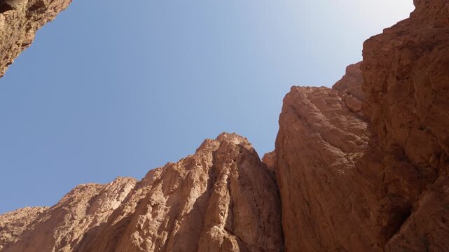 Towering red rock formations of the todra gorge in the high atlas mountains of morocco, a spectacular canyon framing the clear blue sky on a sunny summer day