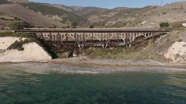 Gaviota, California, USA - Pullback Aerial View of Gaviota Bridge Along U.S. Highway 101 With Pacific Ocean Coastline, Crashing Waves, Rocky Shoreline and Scenic Coastal Freeway on a Sunny 